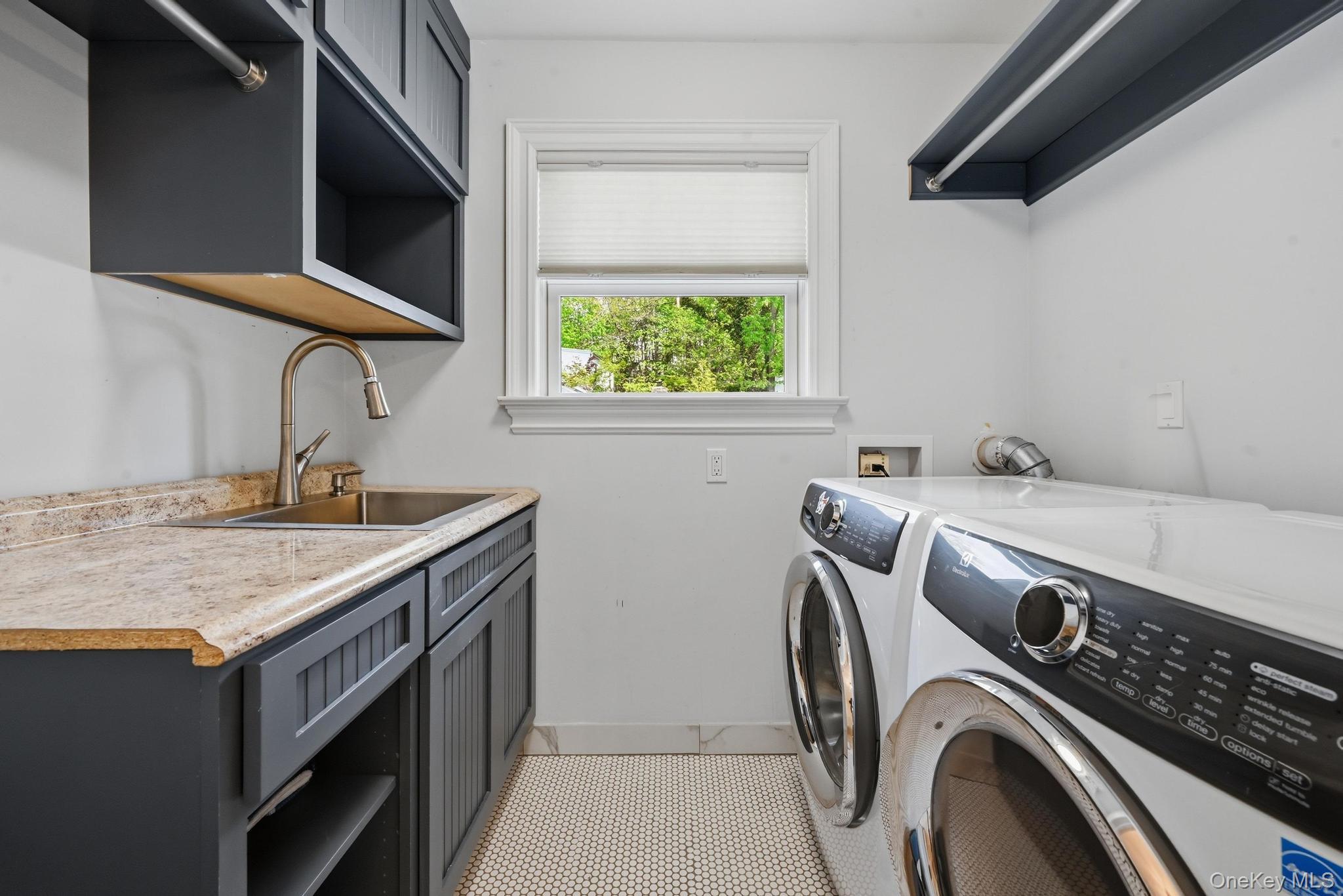 42 Skunks Misery Road Locust Valley, NY 11560 - Photo 34 of 50 Dedicated second floor laundry room featuring dark cabinetry, a utility sink with a gooseneck faucet, light-toned countertop, and a window providing natural light