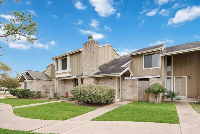 a view of a white house next to a yard with big trees