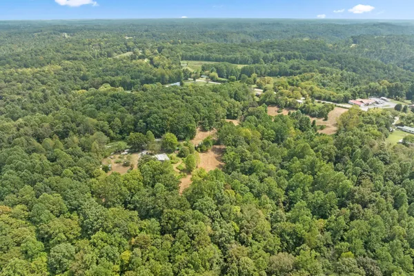 an aerial view of residential house with outdoor space and trees all around