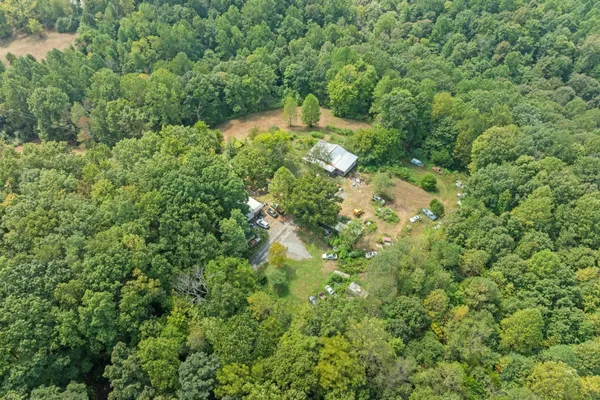 an aerial view of residential house with outdoor space and trees all around
