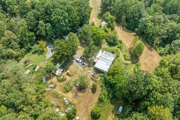 an aerial view of residential house with outdoor space and trees all around