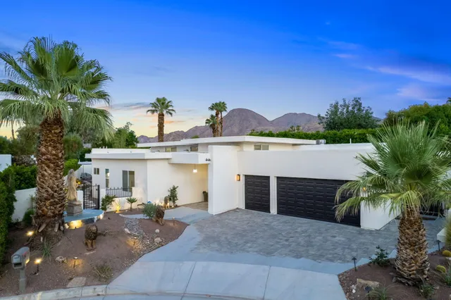a view of a white house with a yard and plants