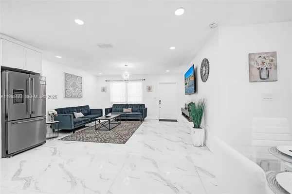 a living room with furniture and a refrigerator