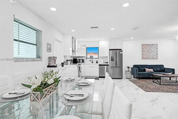 a kitchen with stainless steel appliances kitchen island granite countertop a sink a stove a dining table and chairs with wooden floor