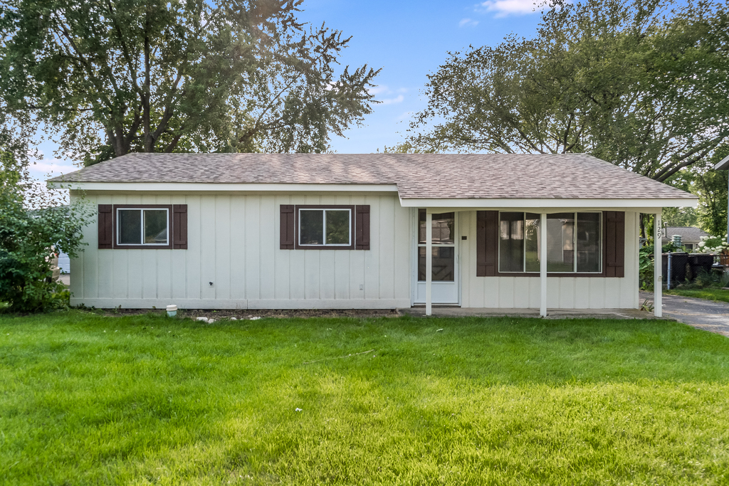 a view of a house with a yard and a large tree