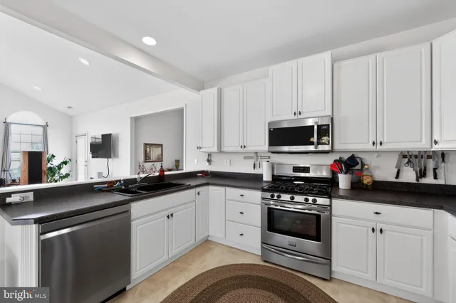 a kitchen with white cabinets sink and appliances