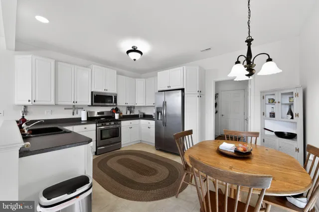 a kitchen with sink a refrigerator and chairs