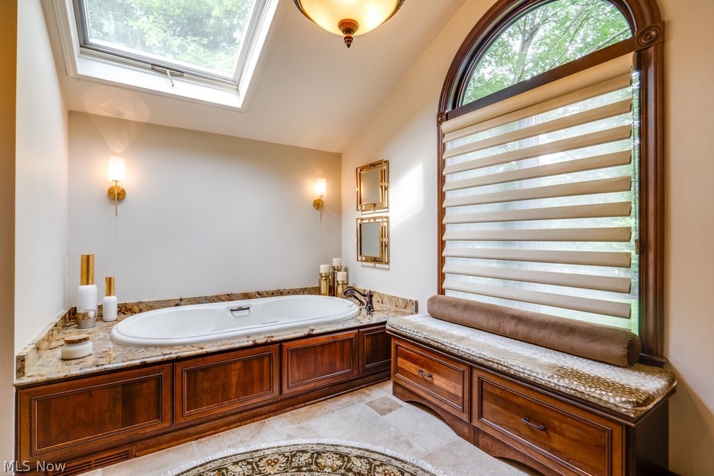 8465 Whitewood Road Brecksville, OH 44141 - Photo 7 of 13 Bathroom featuring a washtub, tile flooring, and vaulted ceiling with skylight