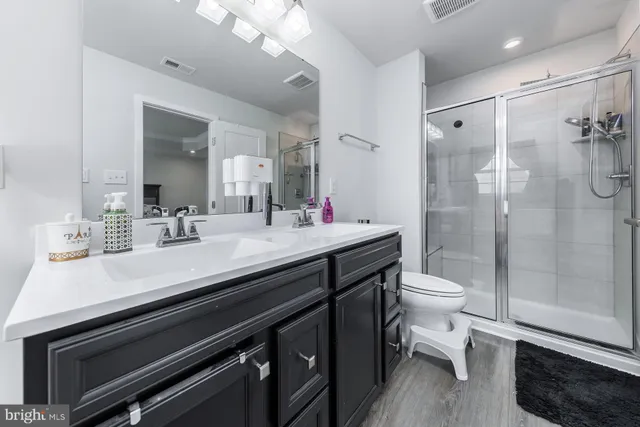 a bathroom with a sink a toilet a mirror and shower