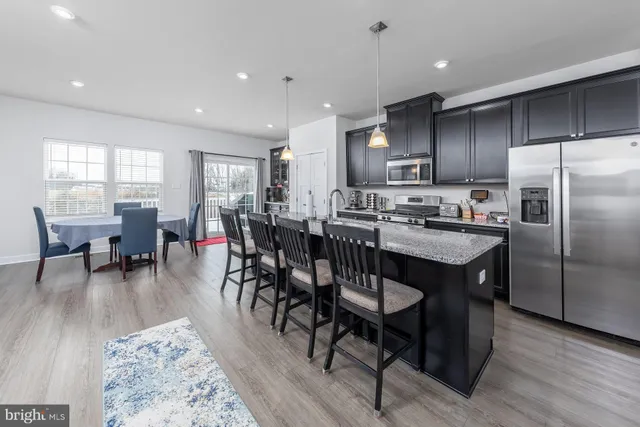 a kitchen with stainless steel appliances granite countertop a table chairs sink refrigerator and cabinets