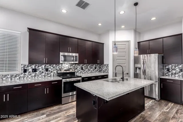 a kitchen with stainless steel appliances kitchen island granite countertop a sink and a refrigerator