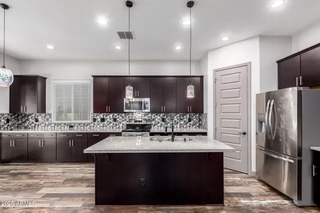 a bathroom with a sink a large mirror and a refrigerator
