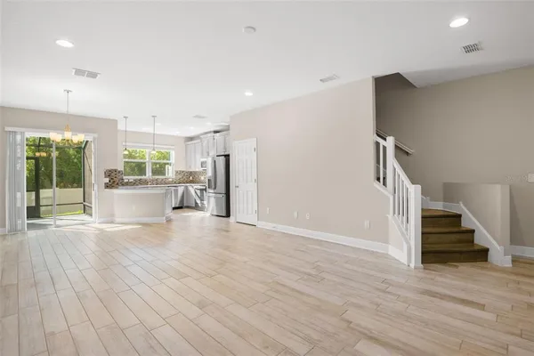 a view of a livingroom with wooden floor and stairs