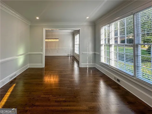 a view of empty room with wooden floor and fan
