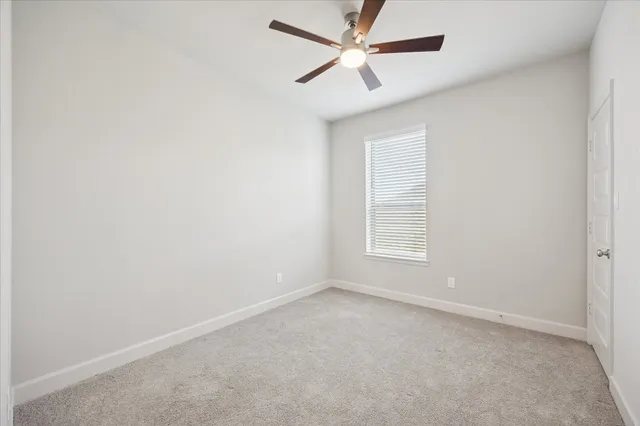 an empty room with a window and a fan