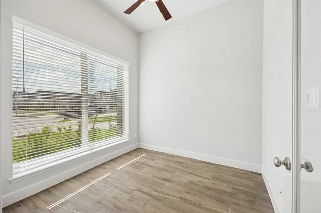 a view of an empty room with wooden floor and a window