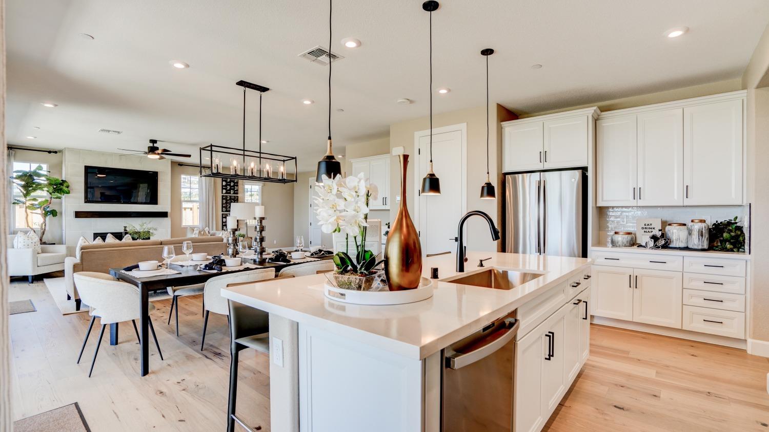 a kitchen with stainless steel appliances kitchen island a white table chairs and a wooden floor