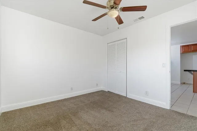 an empty room with closet and a chandelier fan