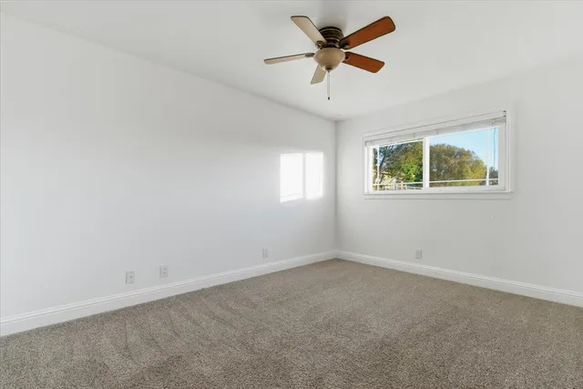 an empty room with a window and a fan