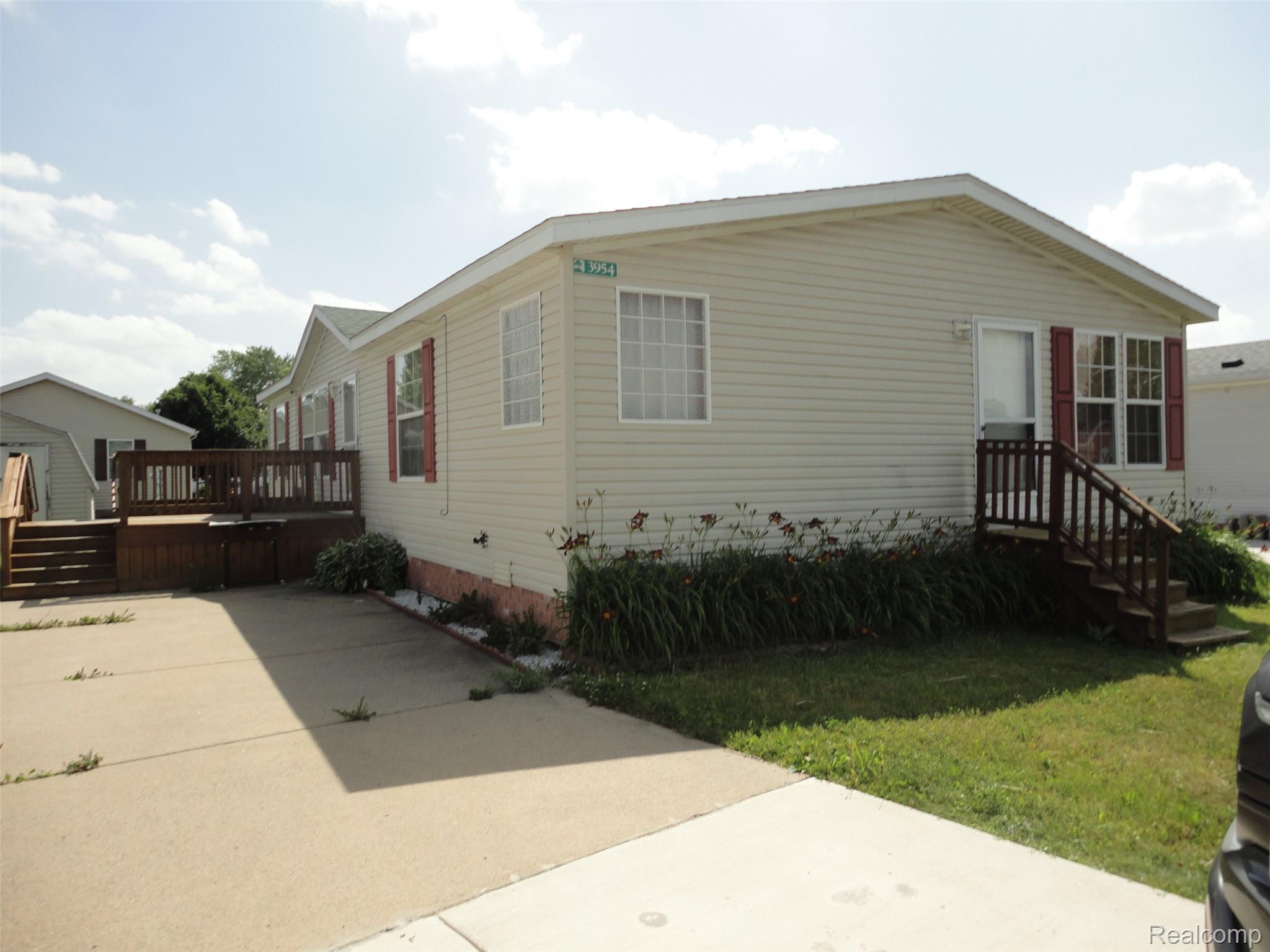 3954 Ryans Ridge Monroe, MI 48161 - Photo 1 of 28 Cream-colored vinyl siding exterior featuring multiple windows with red shutters
