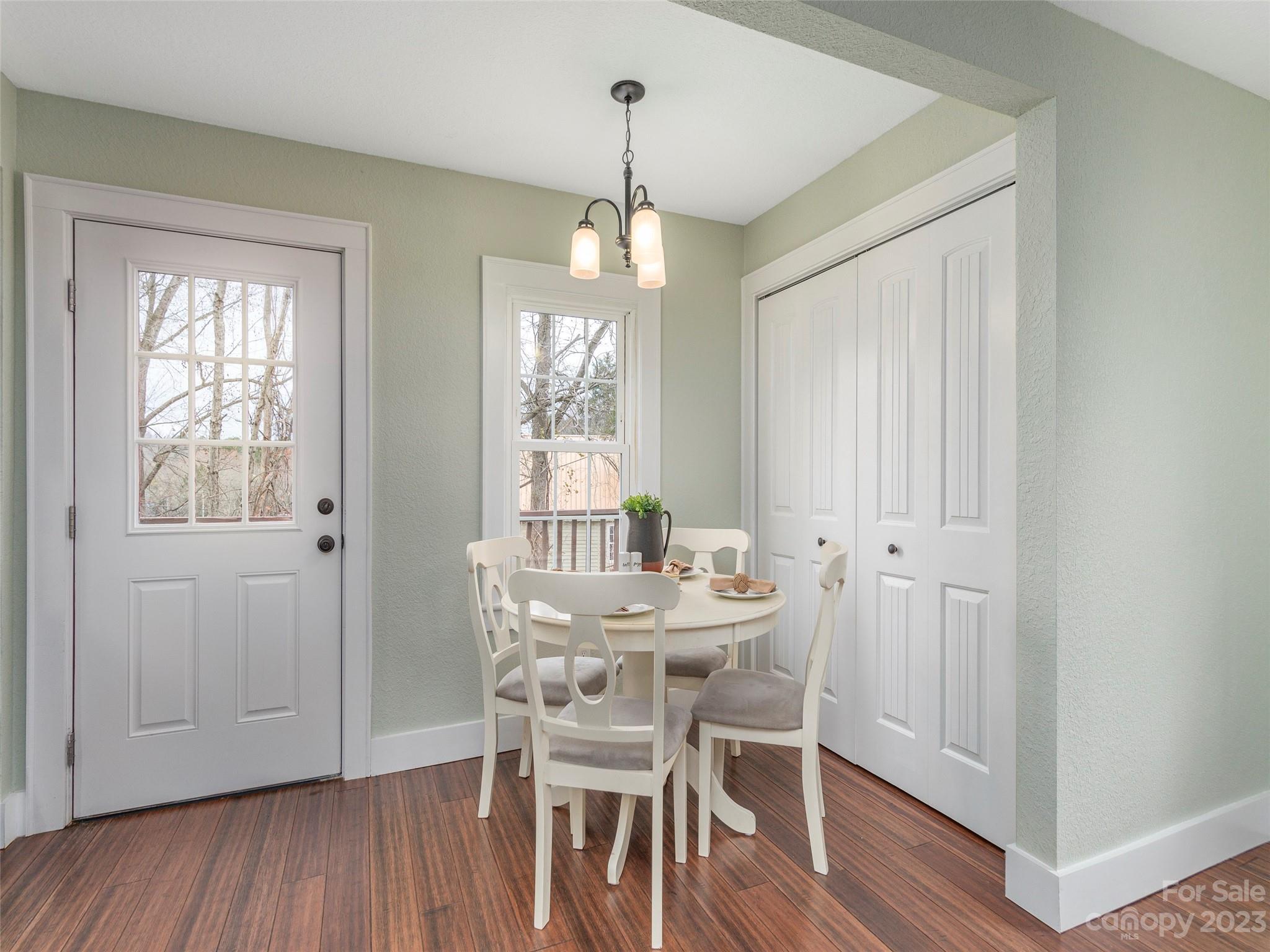 2117 Old Clyde Road Clyde, NC 28721 - Photo 13 of 24 a dining room with wooden floor a chandelier a wooden table and chairs