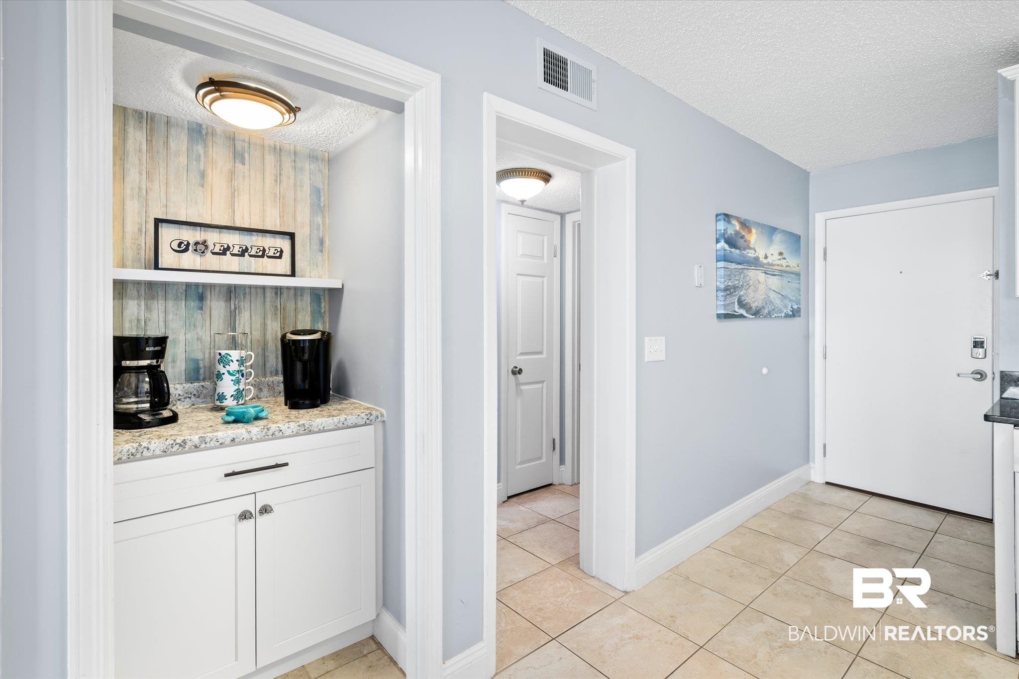 400 Plantation Road, Unit 3222 Gulf Shores, AL 36542 - Photo 6 of 31 Bar with a textured ceiling, light tile patterned floors, white cabinetry, and light stone countertops