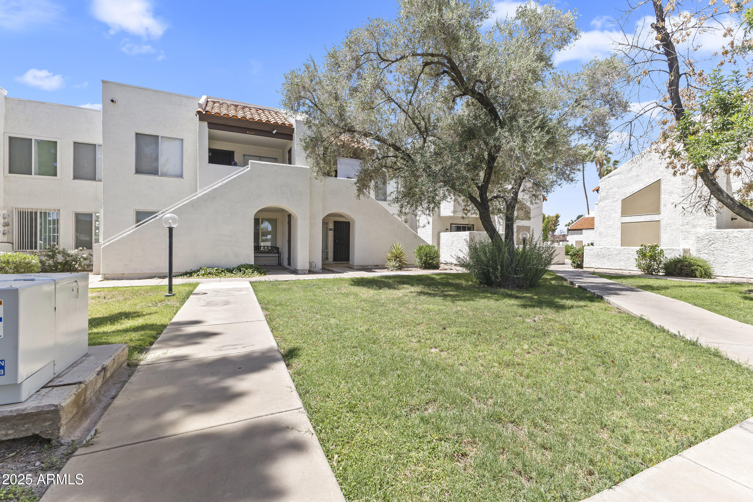 4730 West Northern Avenue, Unit 1158 Glendale, AZ 85301 - Photo 17 of 23 a view of a white house with a big yard plants and large trees