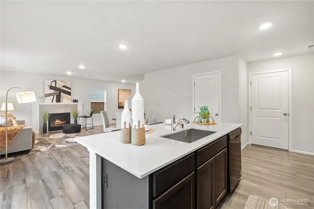 a kitchen with a sink dishwasher and a fireplace with wooden floor