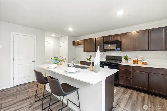 a kitchen with a stove a sink a microwave a dining table and chairs