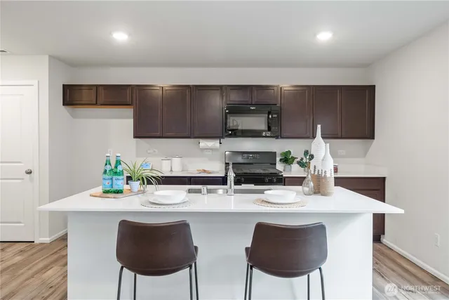 a kitchen with stainless steel appliances a dining table chairs refrigerator and microwave