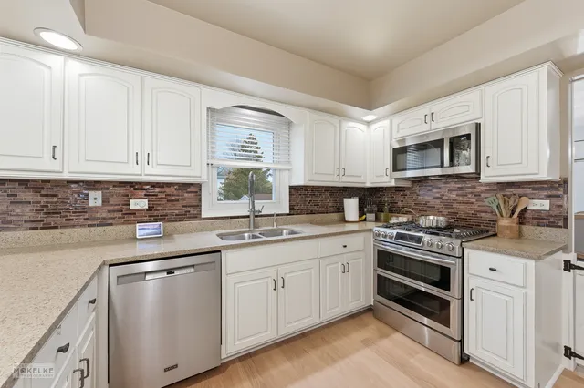 a kitchen with cabinets appliances a sink and a window