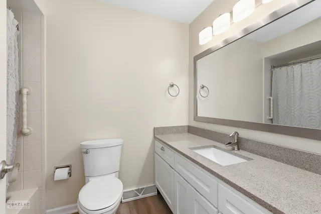 a bathroom with a granite countertop toilet sink and mirror