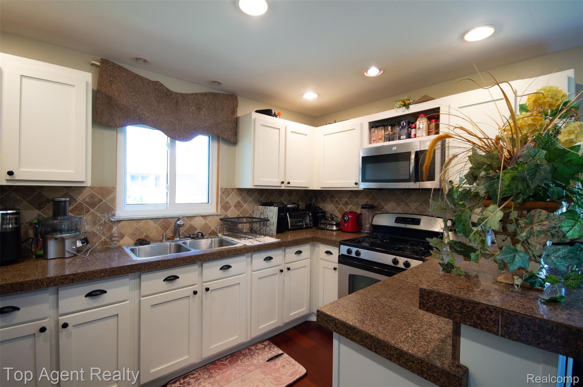 36218 Paddock Drive Clinton Township, MI 48035 - Photo 5 of 22 Kitchen featuring white shaker-style cabinetry, dark granite-look countertops, stainless steel appliances, and a tiled backsplash