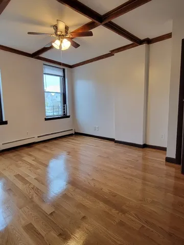 an empty room with wooden floor fan and windows