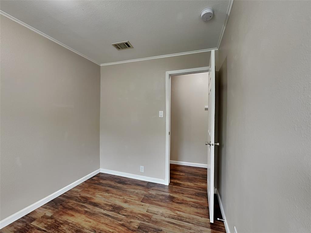 1414 Record Crossing Road Dallas, TX 75235 - Photo 12 of 15 Unfurnished room with a smoke detector, crown molding, and dark wood-type flooring