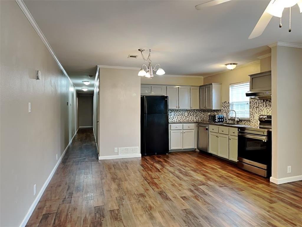 1414 Record Crossing Road Dallas, TX 75235 - Photo 6 of 15 Kitchen featuring appliances with stainless steel finishes, ornamental molding, wood finished floors, backsplash, and under cabinet range hood
