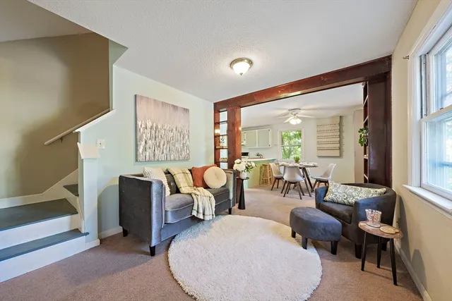 a living room with couches painting on the wall and a large window