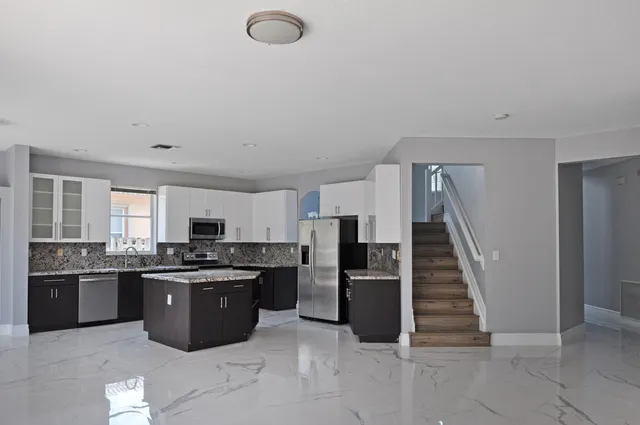 a kitchen with stainless steel appliances granite countertop a stove top oven and refrigerator