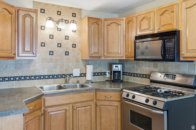 94 West 2000th Street North Clearfield, UT 84015 - Photo 14 of 26 Detailed kitchen view highlighting the tile backsplash, cabinet storage, double sink, gas range, and built-in microwave.