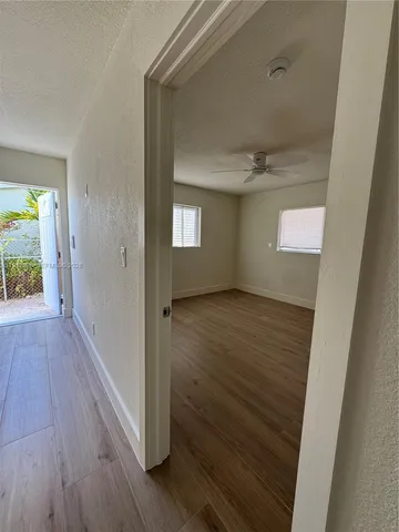 a view of an empty room with wooden floor and a window
