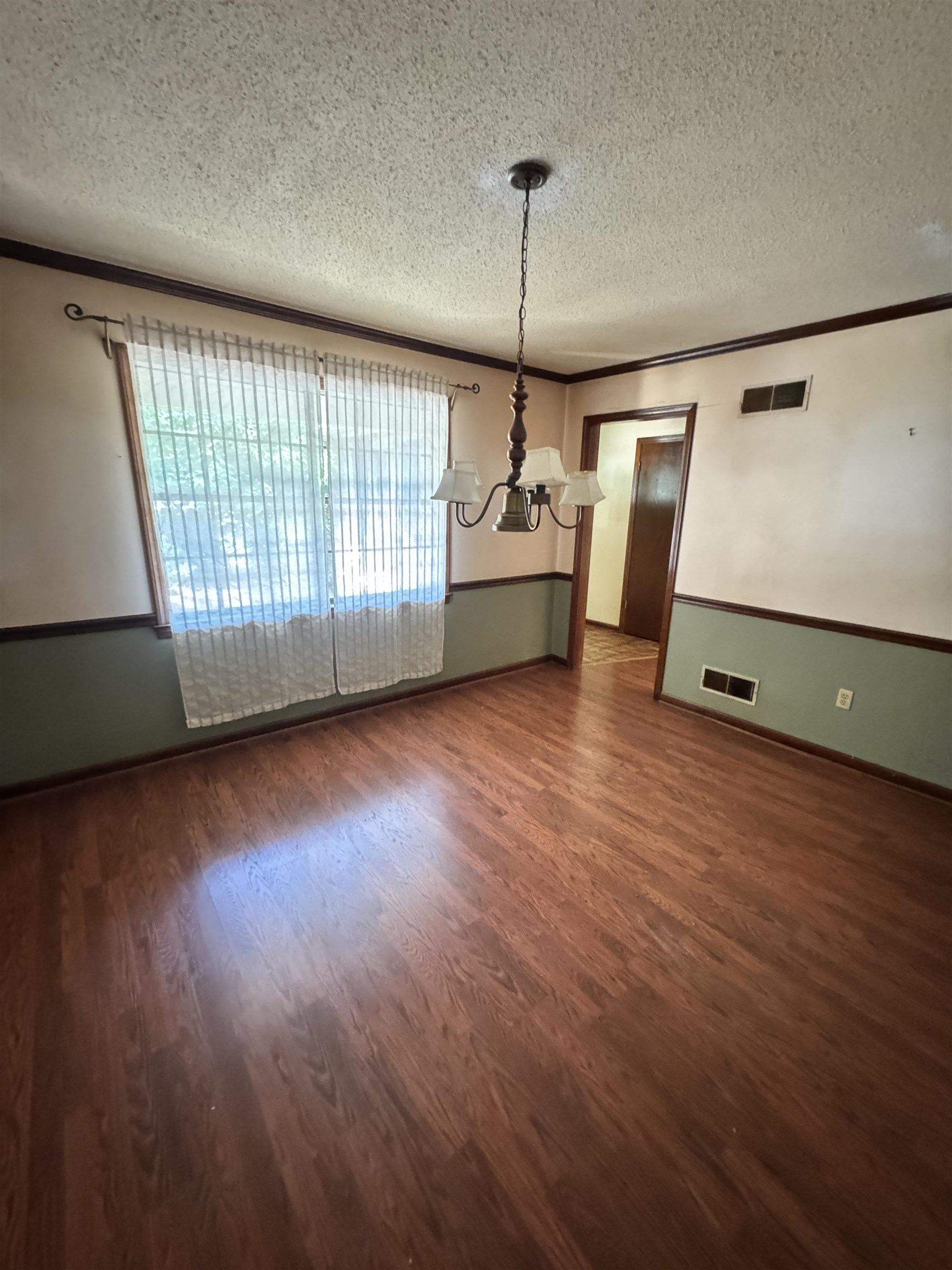 4334 Timber Rise Road Memphis, TN 38125 - Photo 6 of 18 Spacious room featuring wood-finish flooring, a multi-light chandelier, a large window, two-tone wall paint, and dark wood trim