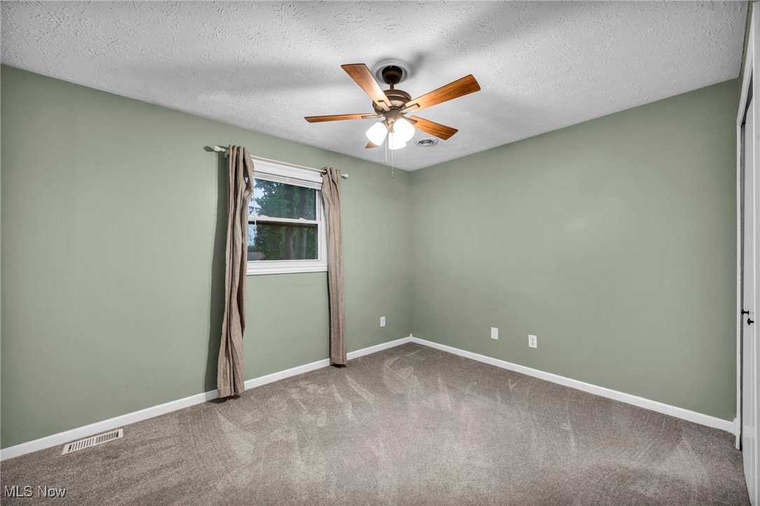 47655 Cooper Foster Park Road Amherst, OH 44001 - Photo 11 of 49 Empty room with ceiling fan, carpet, and a textured ceiling