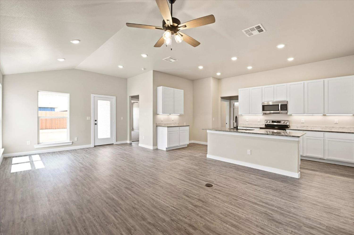 3706 Urbana Place Lubbock, TX 79407 - Photo 5 of 22 an open kitchen with white cabinets wooden floor and a refrigerator