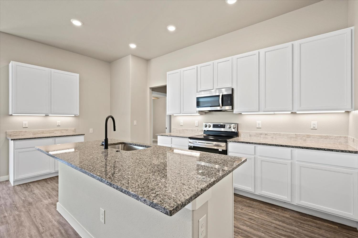 3706 Urbana Place Lubbock, TX 79407 - Photo 9 of 22 a kitchen with granite countertop a sink dishwasher stove and white cabinets with wooden floor
