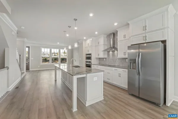 a kitchen with stainless steel appliances a refrigerator a stove top oven and wooden floors