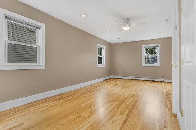 a view of empty room with wooden floor and fan