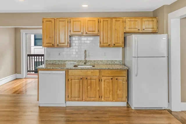 a kitchen with stainless steel appliances granite countertop a refrigerator a stove a sink and white cabinets with wooden floor