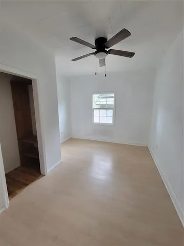 en empty room with windows and ceiling fan
