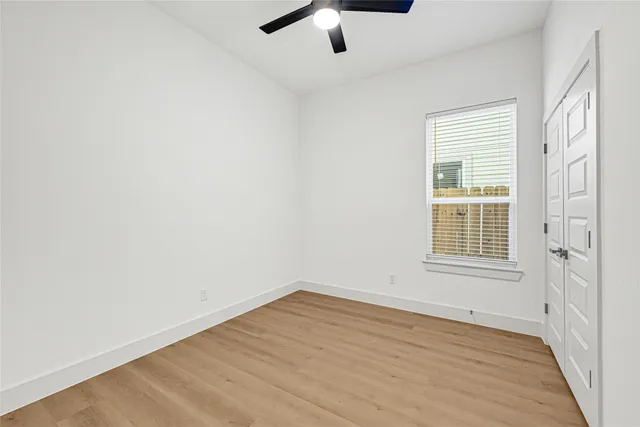 an empty room with a ceiling fan and wooden floor