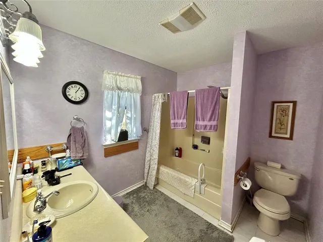 a bathroom with a granite countertop toilet a mirror and shower
